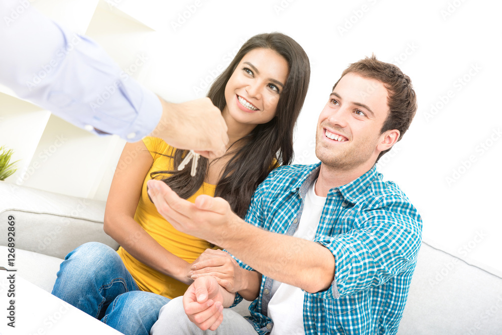 Fototapeta premium Young interracial couple receiving keys from real estate agent
