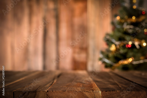 Old wood table top with blur Christmas tree in background