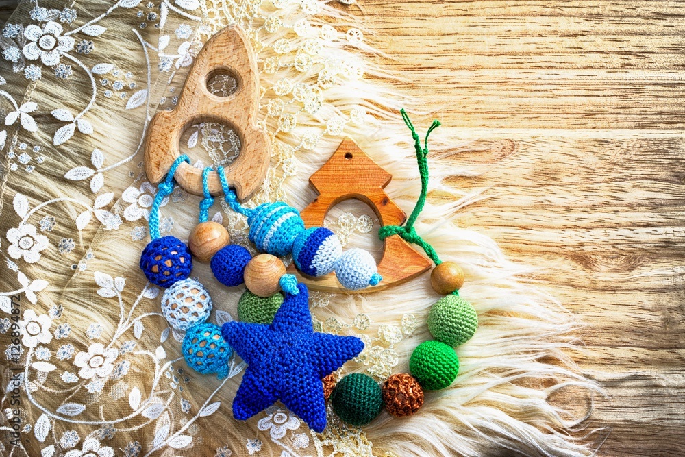 Necklace made from knitted beads and toys for the baby sitting in a sling. Knitted beads. Sling necklace. Spaceship and fir tree. Copy space for your inscription. Necklace made from knitted beads and toys for the baby sitting in a sling. Knitted beads. Sling necklace. Spaceship and fir tree. Copy space for your inscription.