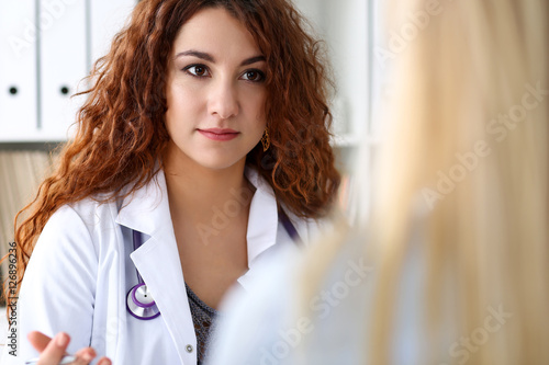 Beautiful female doctor portrait in office with visitor