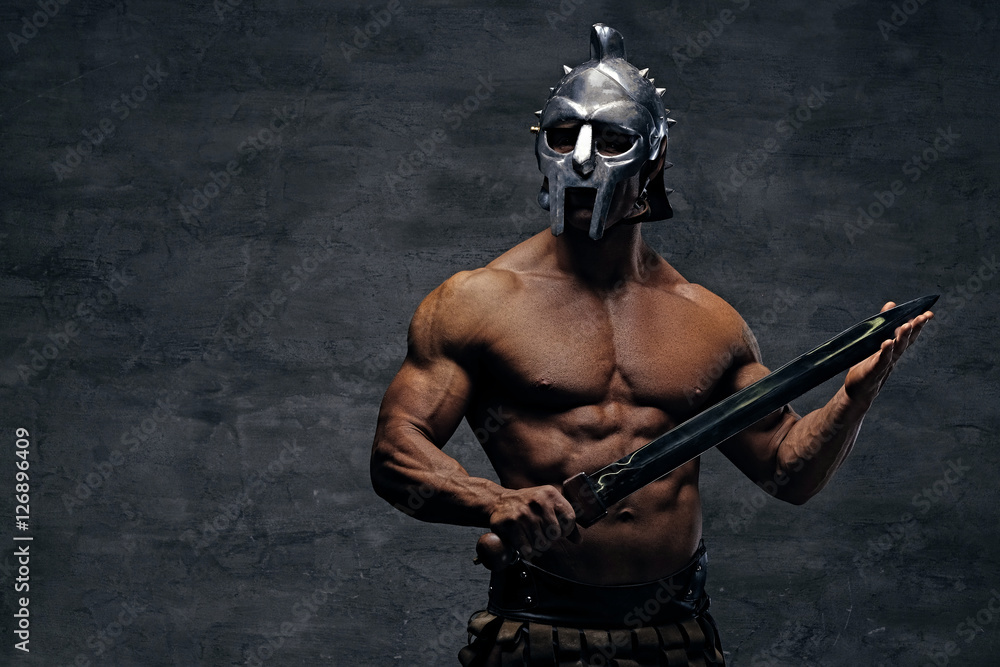 Naklejka premium A man in a silver gladiator helmet holds an iron sword.