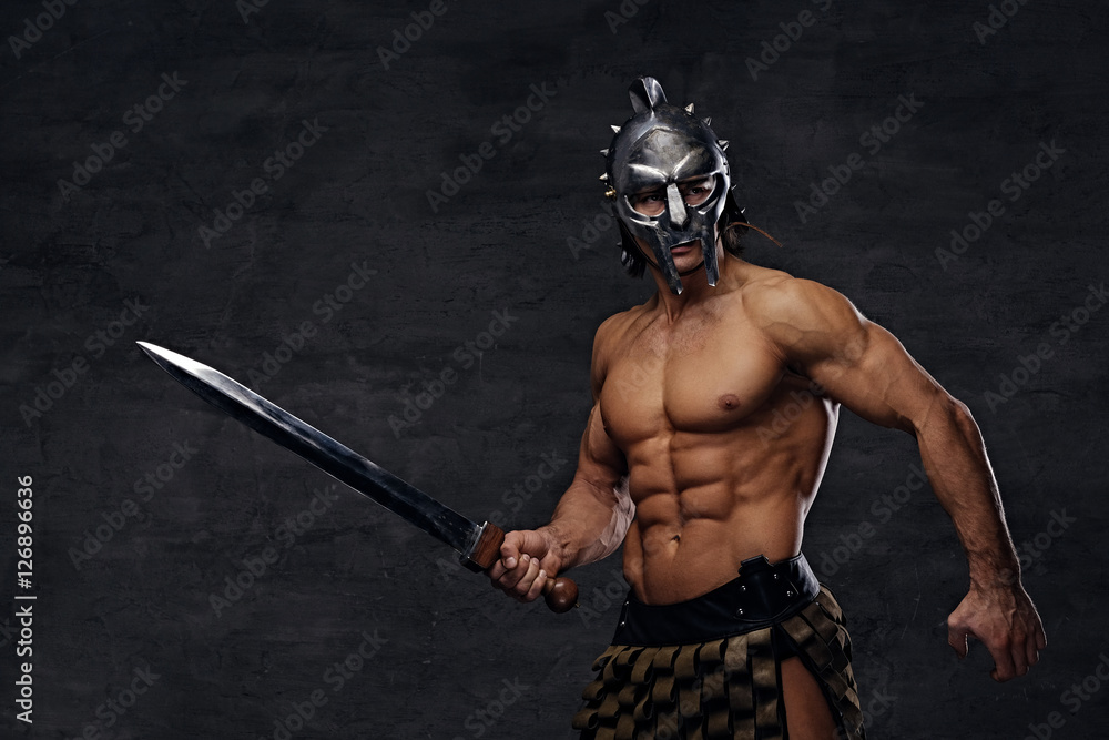 A man in a silver gladiator helmet holds an iron sword. A man in a silver gladiator helmet holds an iron sword.