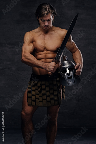 Portrait of shirtless muscular male holds silver gladiator helme