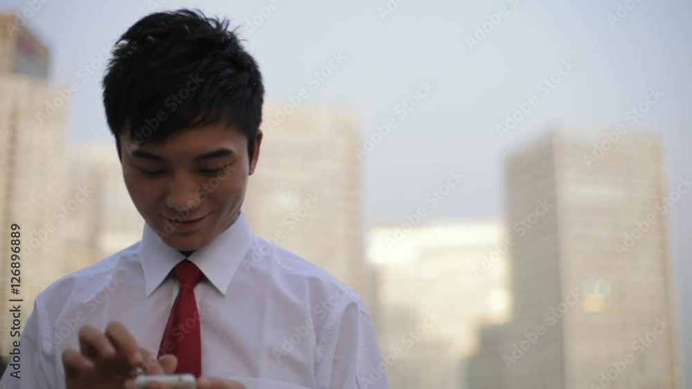 MS TU Businessman text messaging, cityscape in background / Beijing, China MS TU Businessman text messaging, cityscape in background / Beijing, China