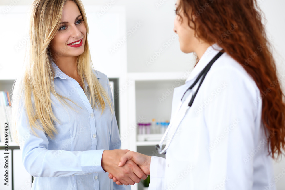 Female doctor shake hand as hello with beautiful blonde patient