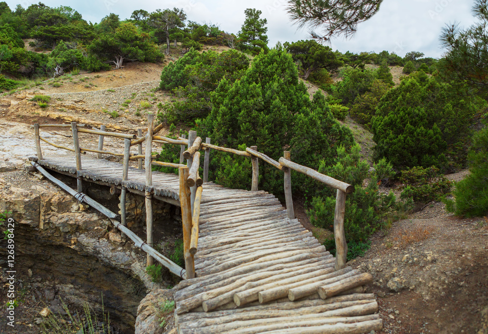 Wooden bridge on Trail Golitsyn - Falcon Path a mountain pathway carved at side of Koba-Kaya. Crimea