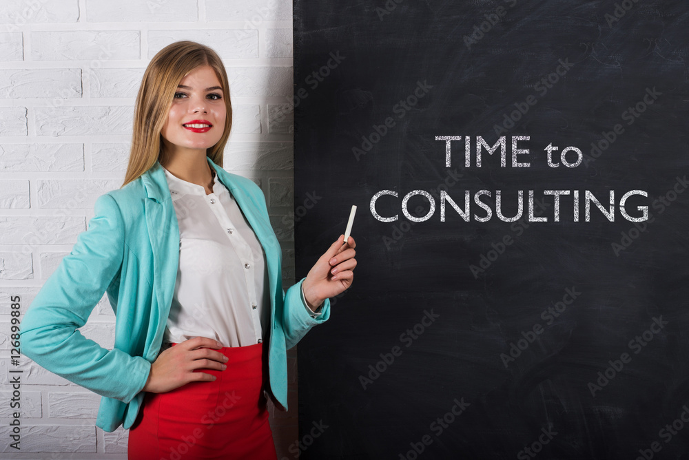 An attractive young woman with chalk at the blackboard with text Time to Consulting An attractive young woman with chalk at the blackboard with text Time to Consulting