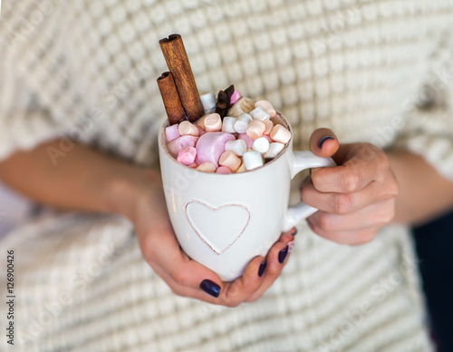 Woman hands holding a cup of hot chocolate with marshmallows photo