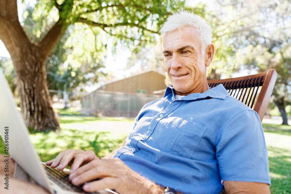 Senior man with notebook sitting in the park Senior man with notebook sitting in the park