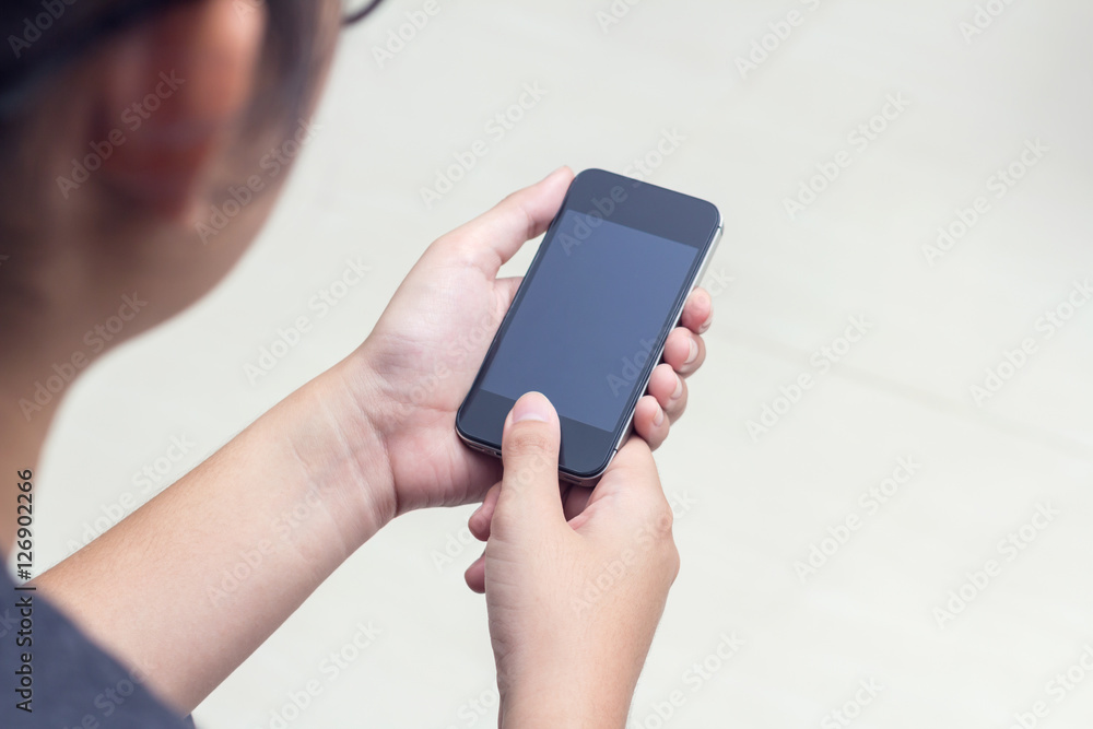 Woman with modern mobile phone in hands touching on a blank scre