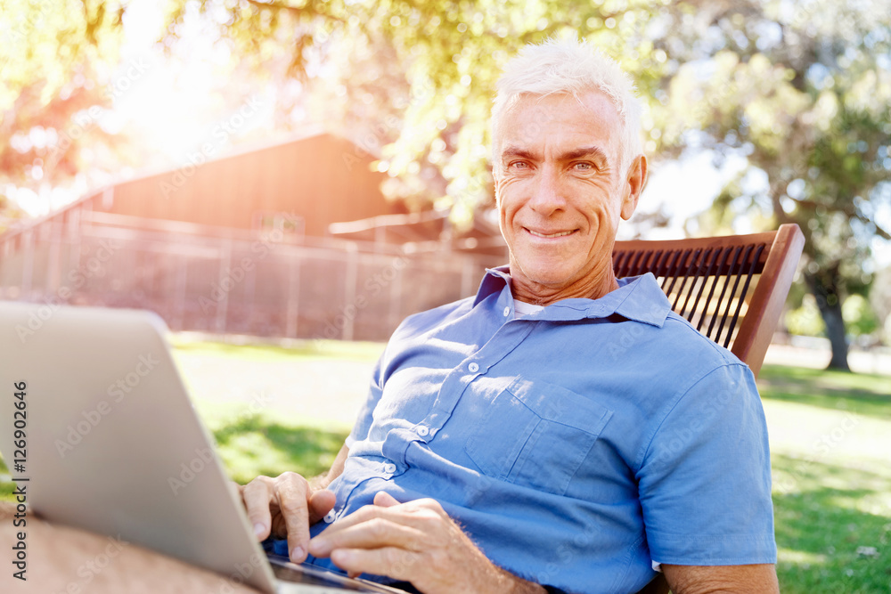 Senior man with notebook sitting in the park Senior man with notebook sitting in the park