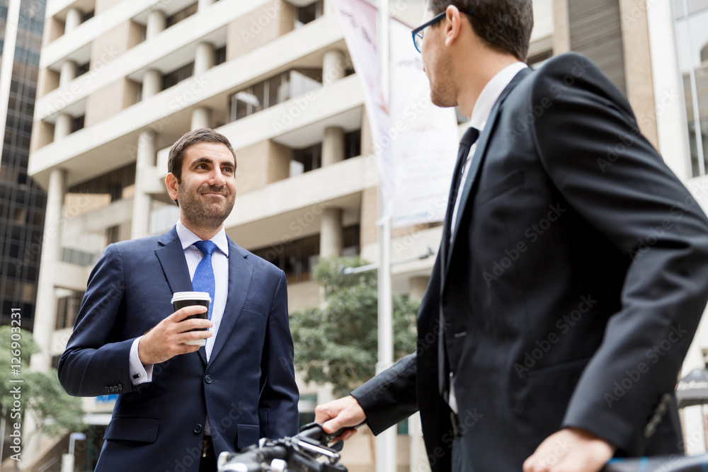 Two young businessmen with a bike in city centre