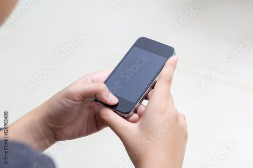 Woman with modern mobile phone in hands touching on a blank scre