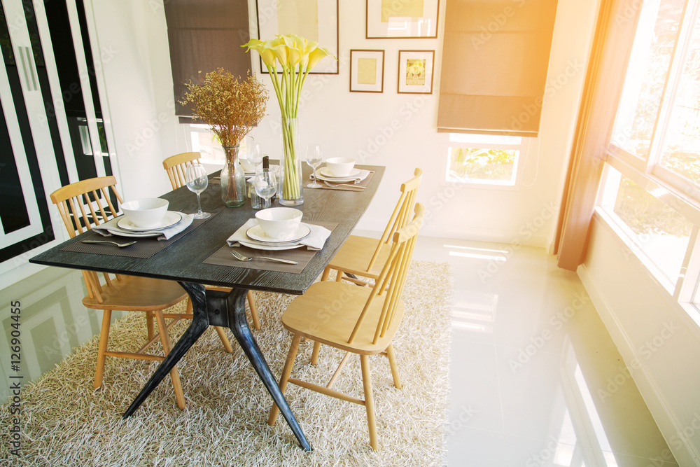 Obraz premium Modern dining room interior with warm light from the sun. Relax day in dining room on free day and no activity. family time with food and enjoy in the family. dining room with table and spoon set.