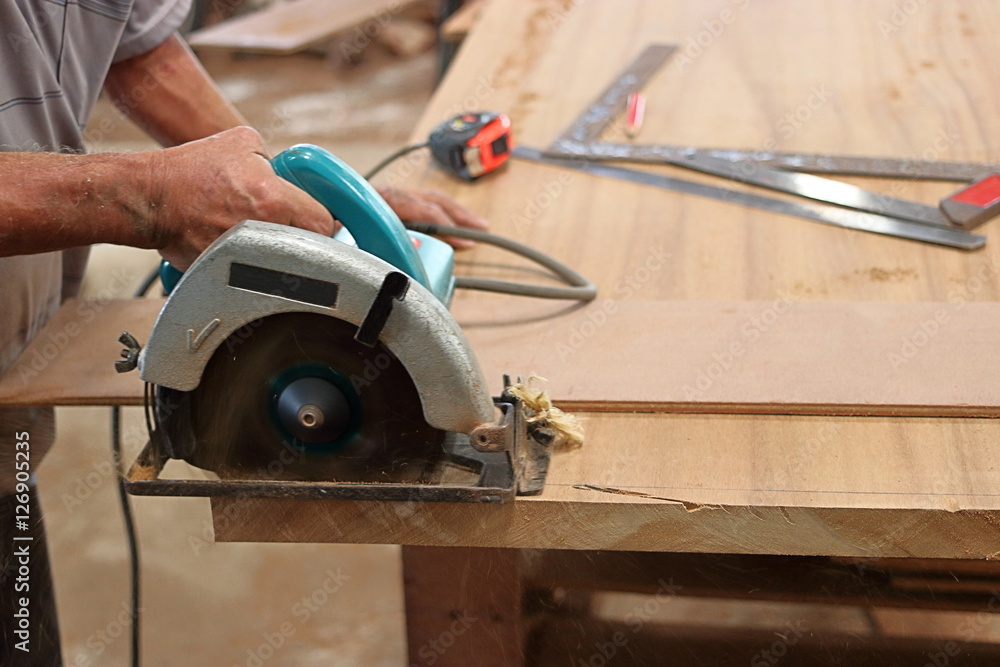 Circular saw cutting piece of wood in carpentry workshop