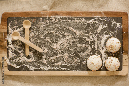 White biscuits are on a wooden board. Background with flour and pastries. 