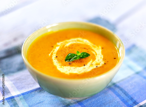 Bowl with pumpkin soup and copy space. Cream soup on a white wooden table.