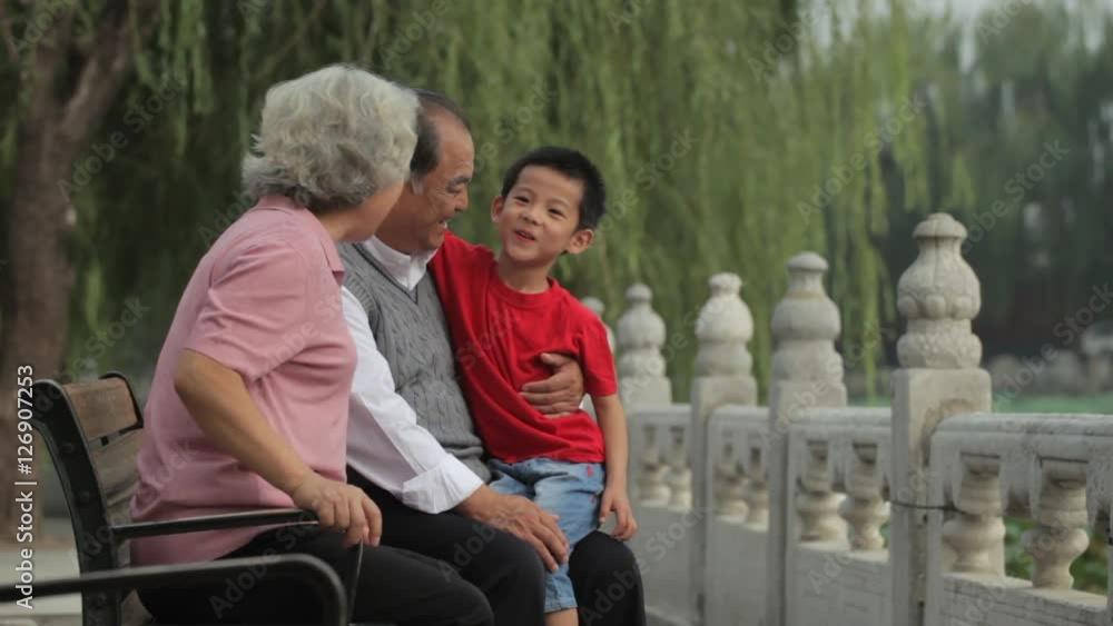 MS Grandparents sitting with their grandson on park bench / China MS Grandparents sitting with their grandson on park bench / China