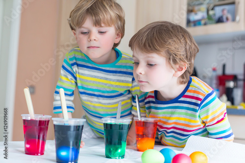 Two little blond kid boys coloring eggs for Easter holiday