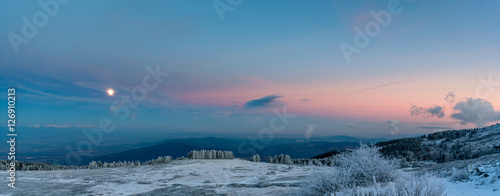 Amazing pink purple winter sunset in the mountains - beautiful frozen landscape - moon rising panorama