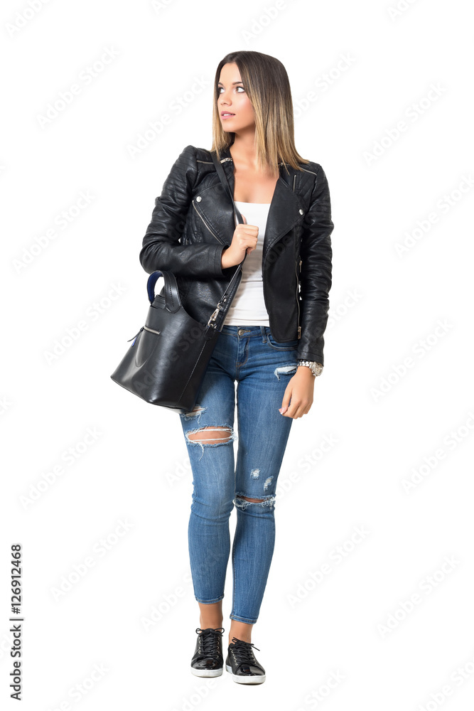 Street style fashion model carrying bag walking and looking away. Full body length portrait isolated over white background Street style fashion model carrying bag walking and looking away. Full body length portrait isolated over white background