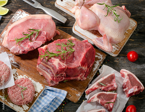 Different types of fresh raw meat with fresh vegetables and herb photo