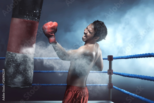 Asian man boxer practicing with punching bag