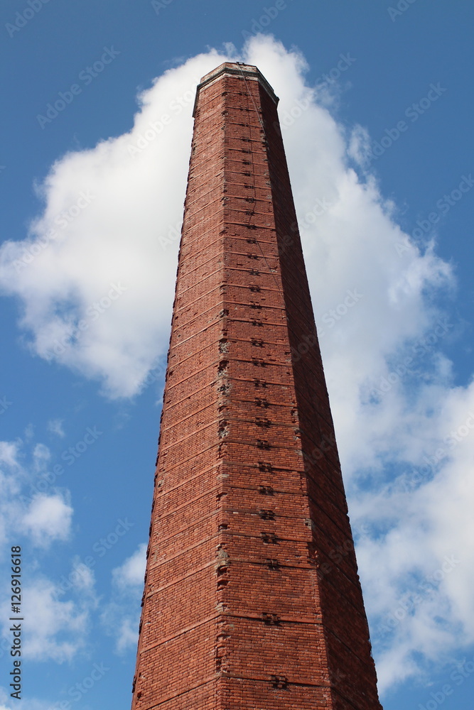 old factory chimney in red brick against the blue sky