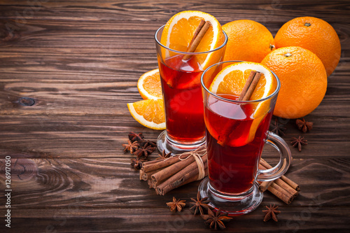 Glass with mulled wine, spices and fruits on wooden background