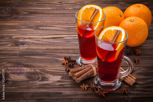 Glass with mulled wine, spices and fruits on wooden background