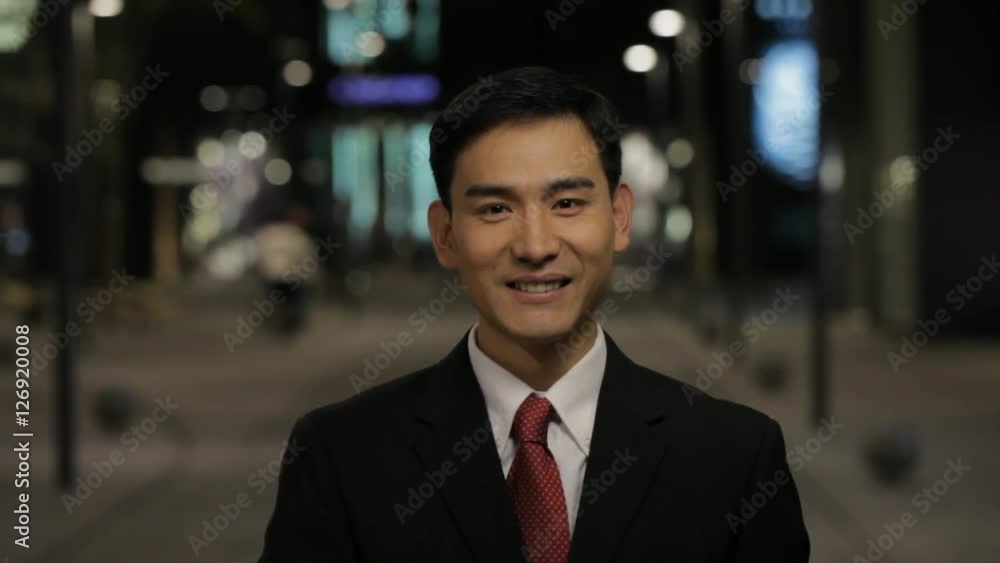 CU Portrait of businessman taking off his glasses and smiling, standing on street at night / China CU Portrait of businessman taking off his glasses and smiling, standing on street at night / China