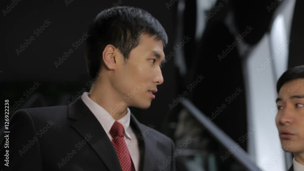 MS Two businessmen talking to each other moving down on escalator / China MS Two businessmen talking to each other moving down on escalator / China