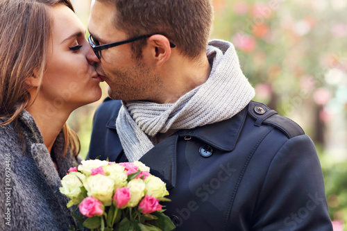 Young couple with flowers kissing in the park