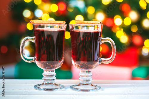 Beautiful Two glasses of mulled wine on bokeh background decorated Christmas tree. The idea for postcards. Soft focus. Shallow DOF