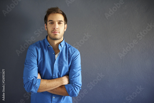 Young man portrait with copy space. Close-up shot of a handsome young man standing in front of a grey wall.