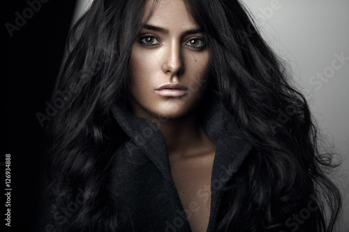 Fashion portrait of a sensual brunette girl with curly long black hair.