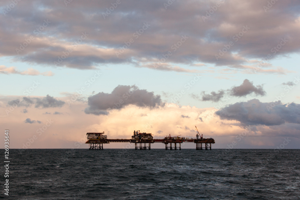 Silhouette of oil rig platform during sunset at oilfield