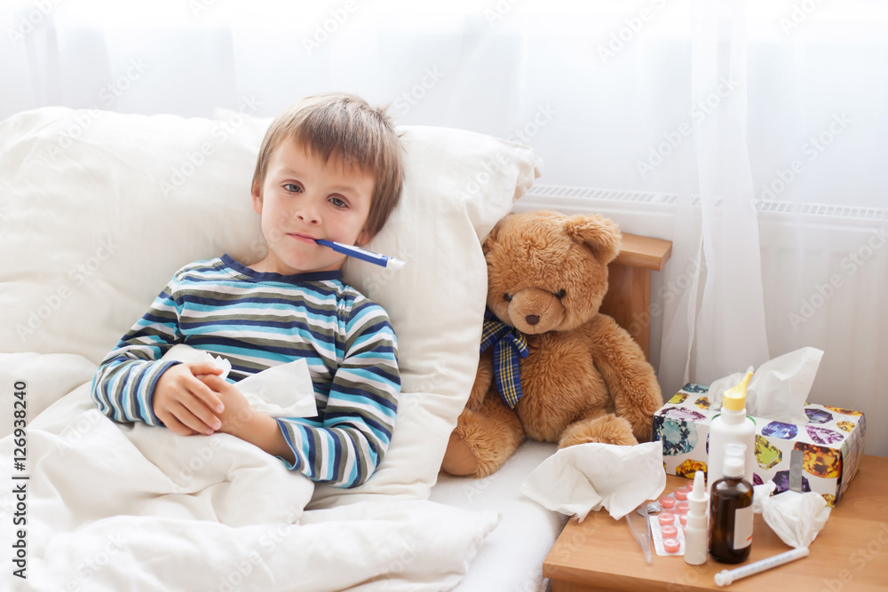 Sick child boy lying in bed with a fever, resting Sick child boy lying in bed with a fever, resting