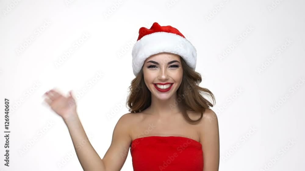 Happy young woman in red santa claus costume turns around and waving hand Happy young woman in red santa claus costume turns around and waving hand