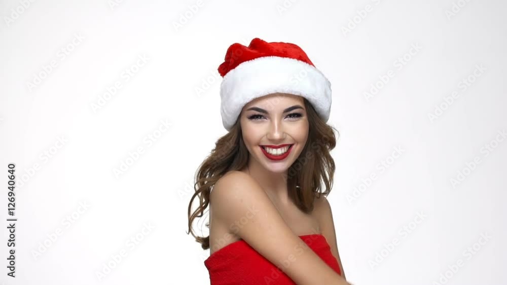 Happy young woman in red santa claus costume turns around and pointing finger at camera Happy young woman in red santa claus costume turns around and pointing finger at camera