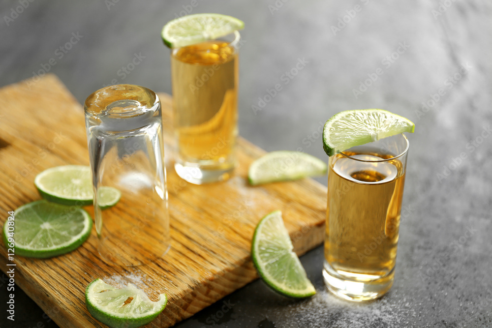 Gold tequila shots with lime and salt on gray table Gold tequila shots with lime and salt on gray table