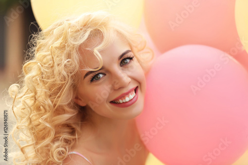 Beautiful young woman holding air balloons on street © Africa Studio
