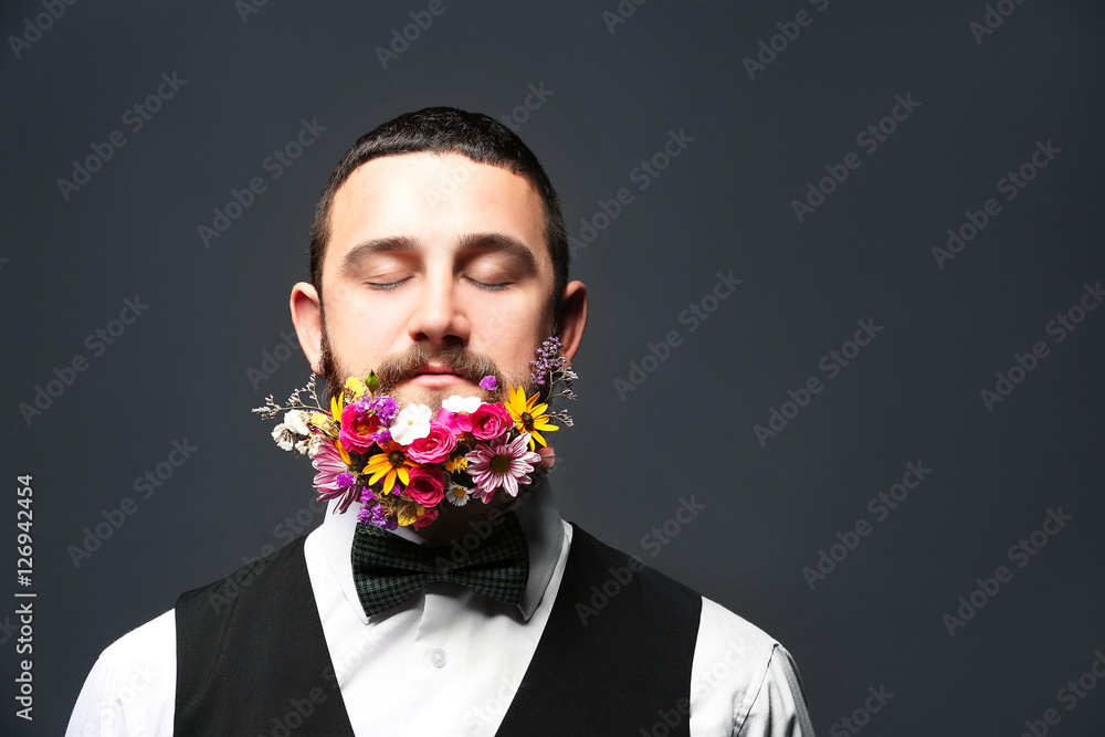 Handsome man with beard of flowers on dark background Handsome man with beard of flowers on dark background