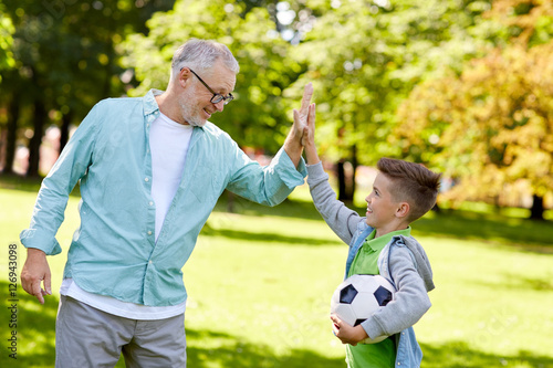 old man and boy with soccer ball making high five © Syda Productions