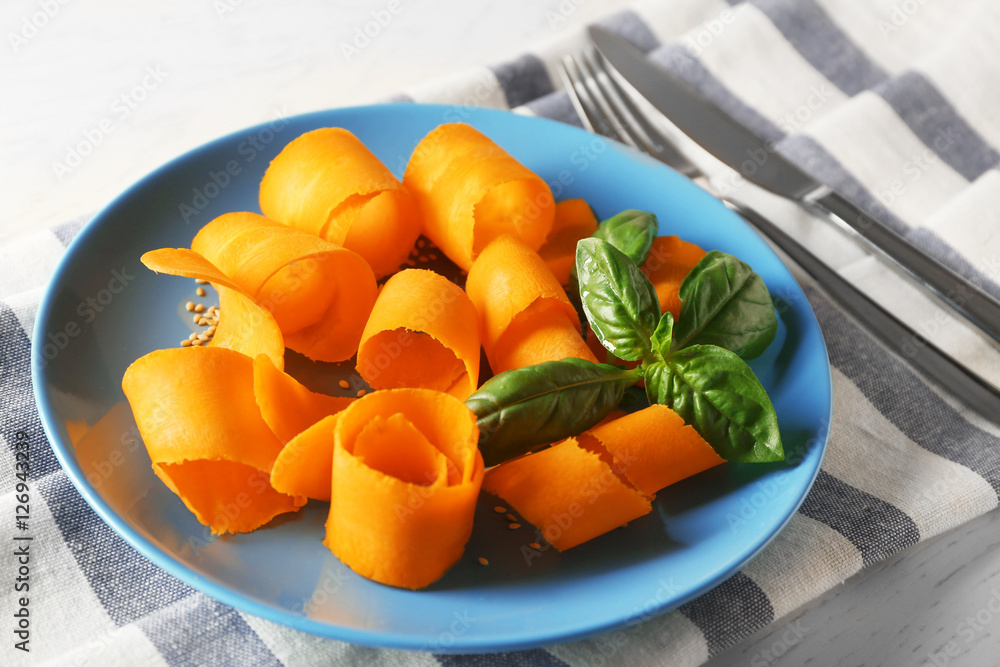 Blue plate with sliced carrot and basil on napkin Blue plate with sliced carrot and basil on napkin