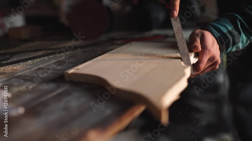 Close-up of a Carpenter working on a Wooden Window Frame with a File in his Workshop.