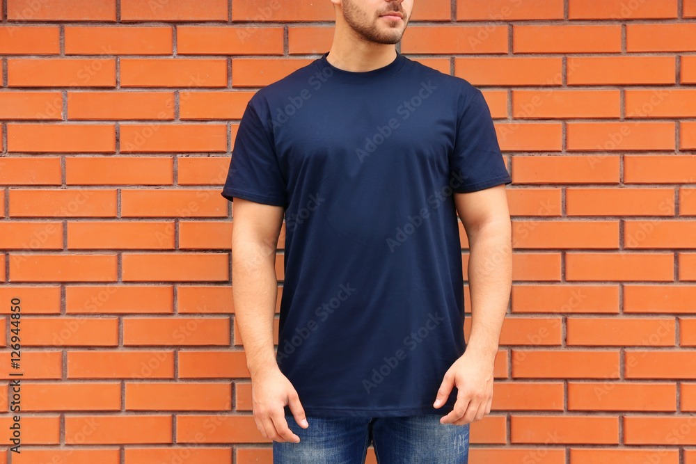 Young man in blank t-shirt standing against brick wall, closeup Young man in blank t-shirt standing against brick wall, closeup