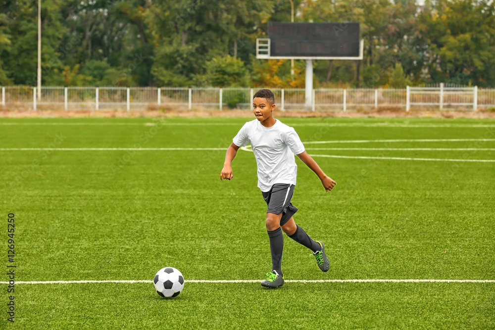 Boy playing football at stadium