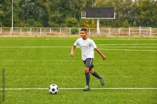Fototapeta Naklejka Na Ścianę i Meble -  Boy playing football at stadium