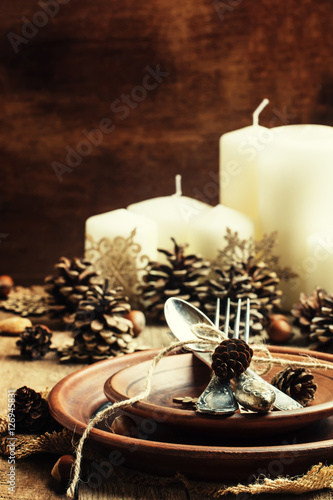 Table setting with pine cones, candles and snowflakes, pottery, photo